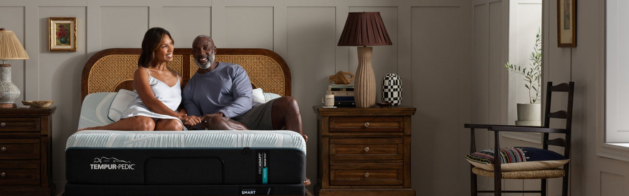 Man lays back with an arm behind his head on an Active Breeze tempur mattress with the remote to the adjustable base in his hand, the head of the bed is tilted up slightly